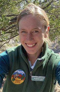 安吉拉站在一片沙漠中, 穿着一件绿色羊毛背心，左边有亚利桑那-索诺拉网上买球十大正规平台的徽章.